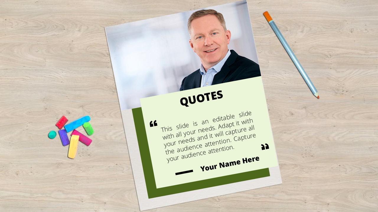 Quote card with a green border and a professional man's photo, placed on a wooden surface with colorful chalk and a pencil.