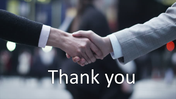 Thank you slide featuring a close-up handshake with a text overlay in a professional setting.